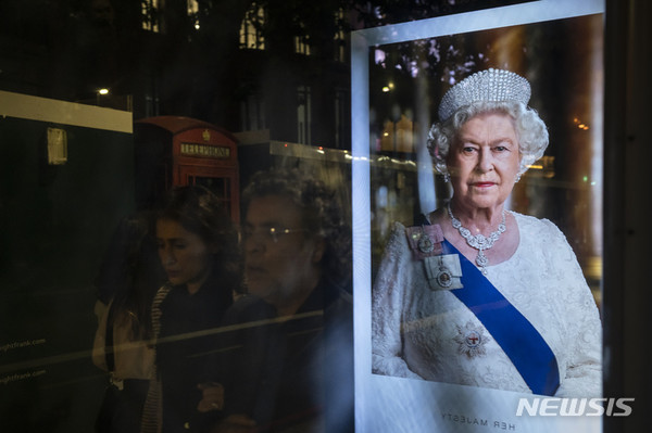 [런던=AP/뉴시스]9일(현지시간) 런던의 버스 정류장에 비친 엘리자베스 2세 여왕의 사진 옆을 사람들이 지나가고 있다. 영국에서 가장 오래 재위한 군주이자 격동의 세기 동안 안정의 바위였던 엘리자베스 2세 여왕이 9일 서거했다.2022.09.10.