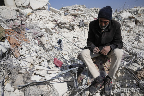 [아타렙=AP/뉴시스] 12일(현지시간) 시리아 아타렙의 지진 피해 현장에서 한 남성이 건물 잔해 위에 앉아 있다. 2023.02.13.